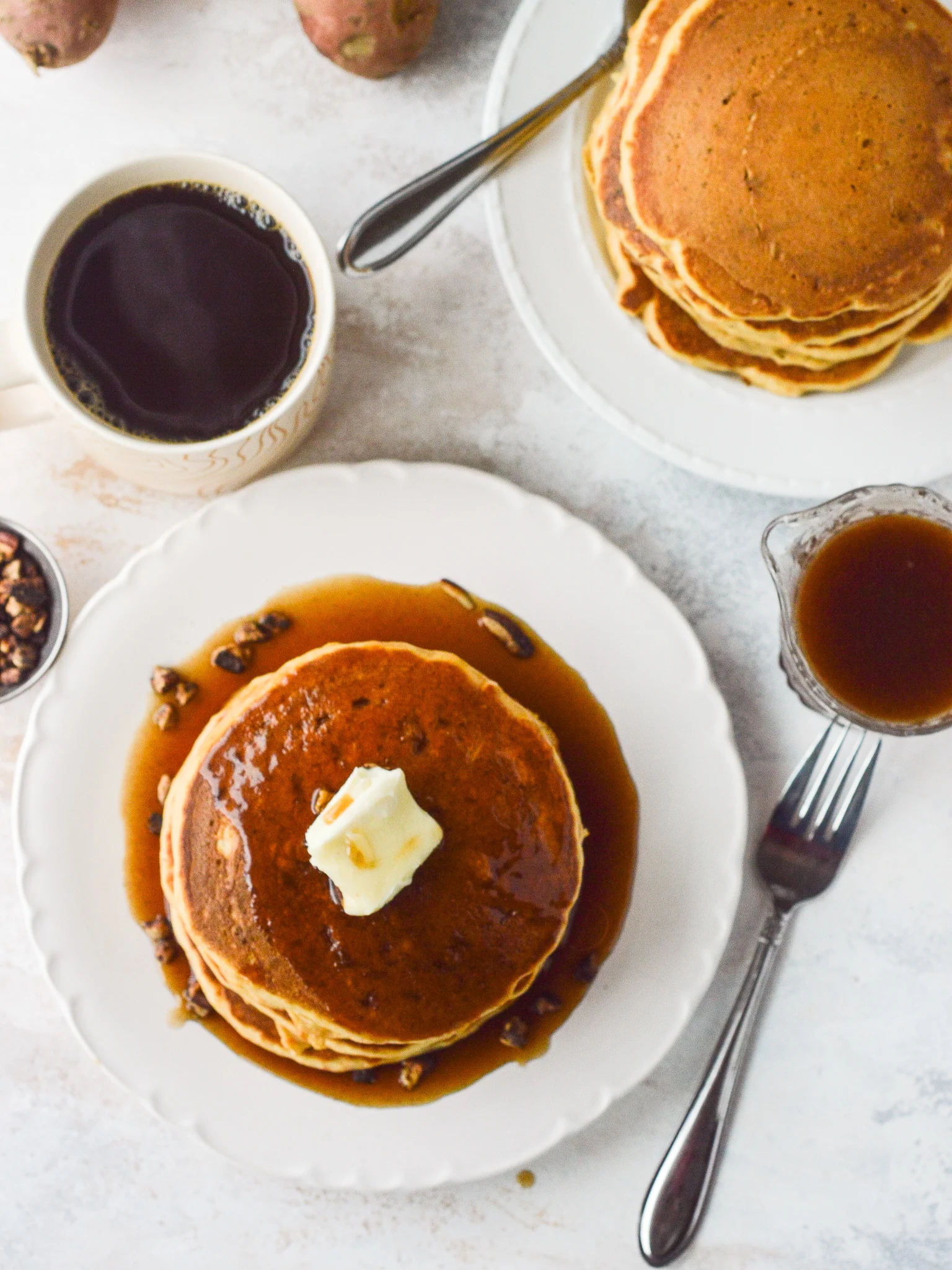 Overhead table-scape of a pancake breakfast with coffee and a carafe of cinnamon syrup