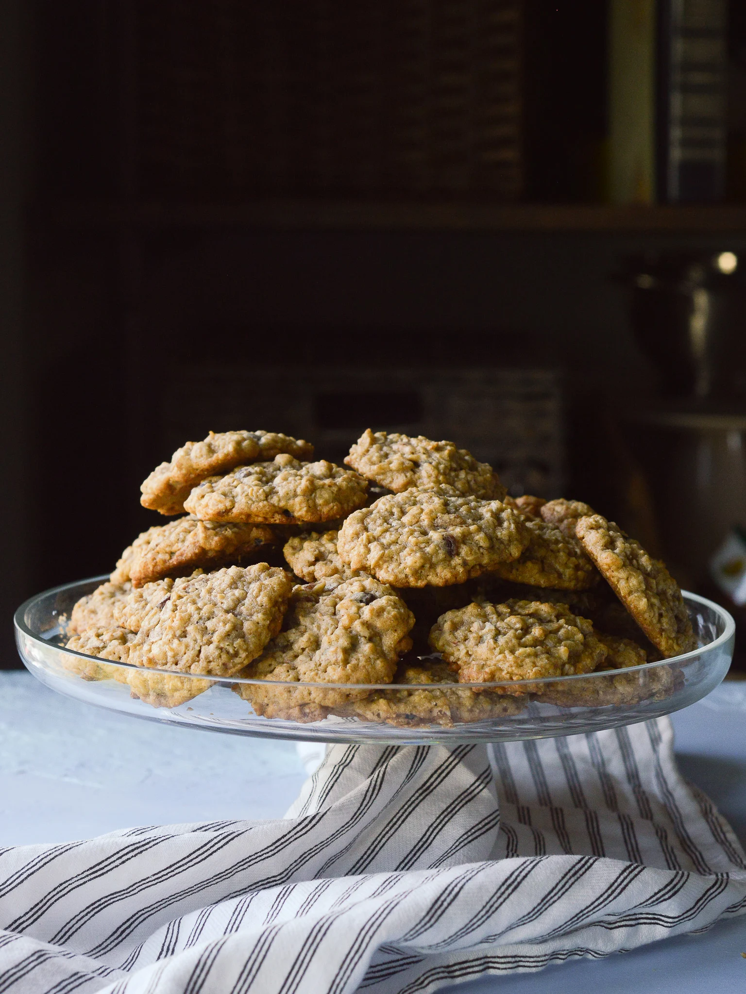 A cake stand piled high with classic oatmeal raisin cookies that are chewy with a slightly crisp edge. 